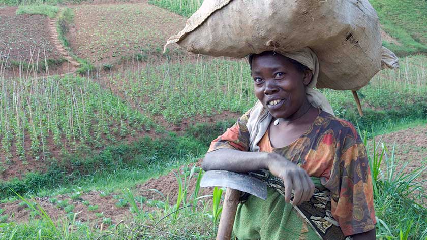 A farmer in Rwanda standing in front of her land.