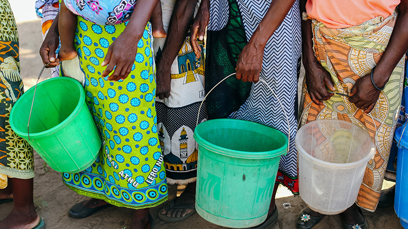 Women in Malawi wait to fill their buckets with water at a community water point. 