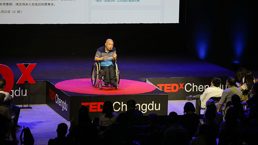 A speaker who uses a wheelchair presenting on the main stage at TEDxChengdu Skoll