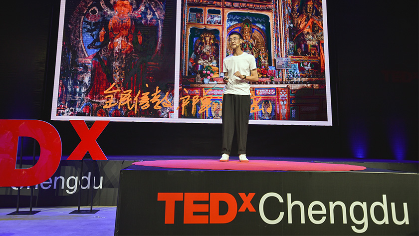 A speaker presenting on the main stage at TEDxChengdu Skoll