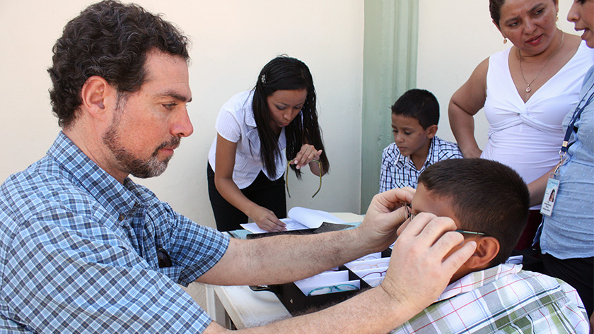 Jordan Kassalow sizes a new pair of eyeglasses for a boy in El Salvador. 