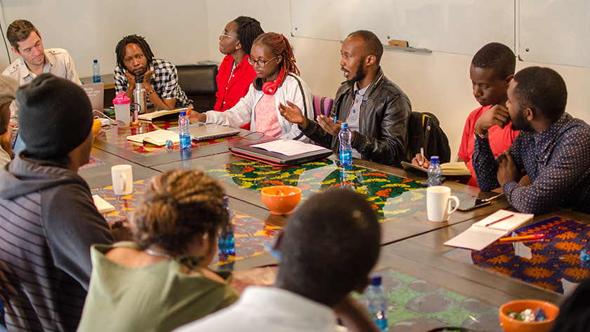 A group of Docubox workshop filmmakers sit around a table