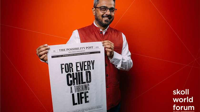 Vishal Talreja at the 2019 Skoll World Forum, holding up a screenprinted newspaper with the headline "For Every Child A Thriving Life"